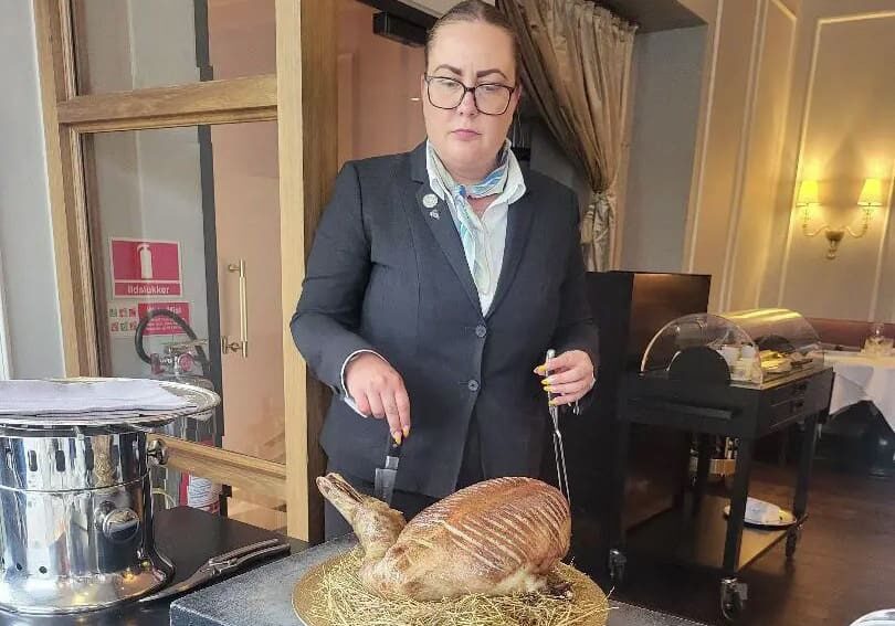 Woman in suit carving roasted duck.