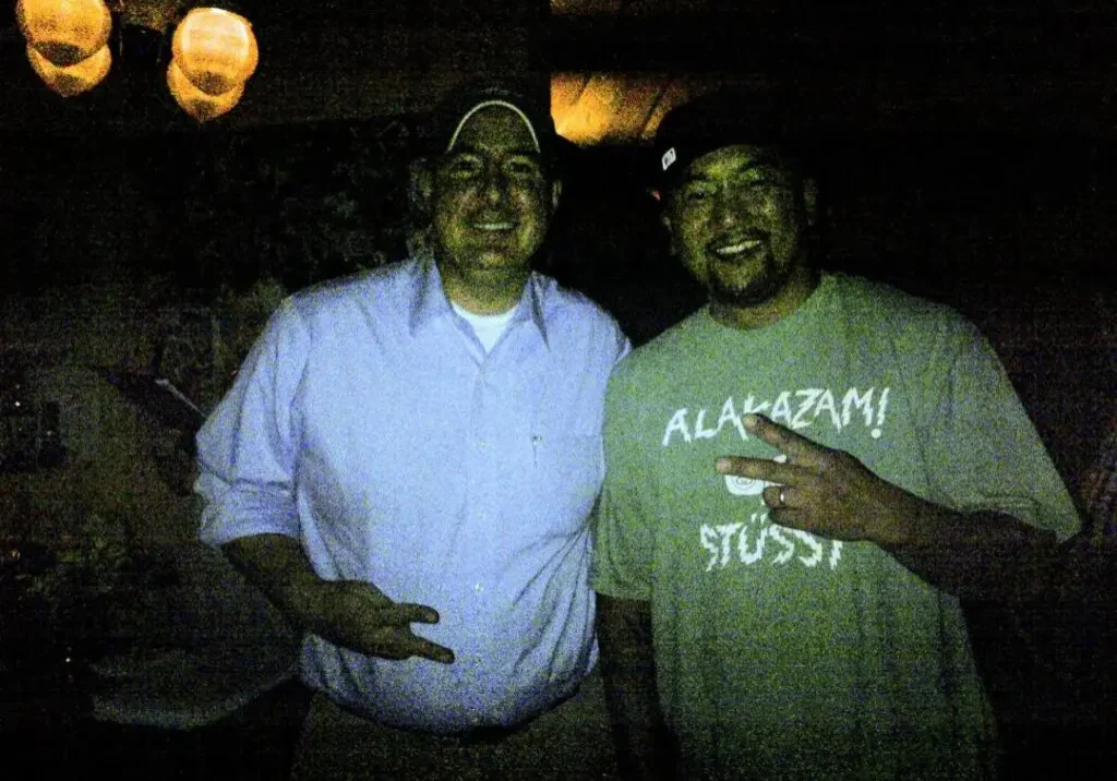 Two men standing next to each other in a dark room.