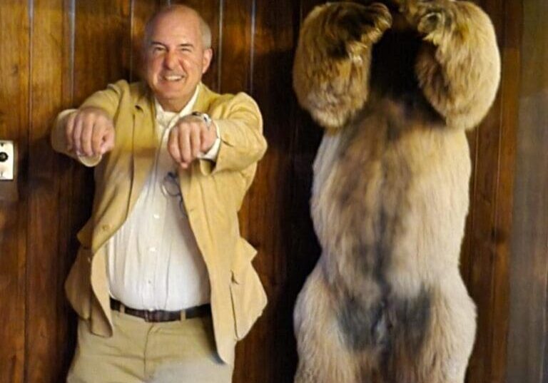 A man posing next to a bear statue.